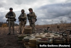 Бійці спецпідрозділу з розмінування Нацполіції стоять біля знешкоджених протитанкових мін